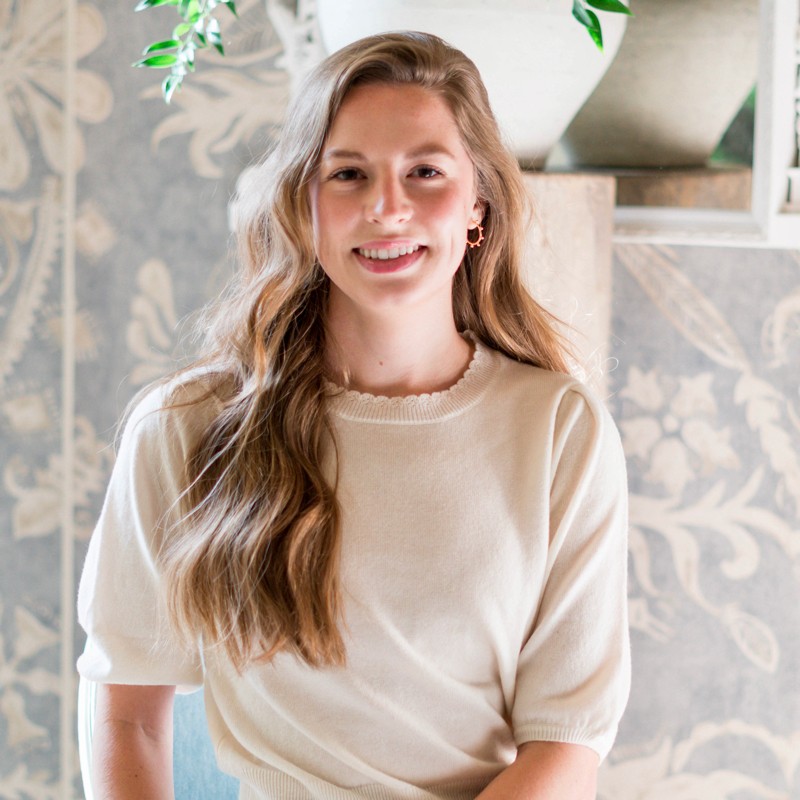 Amelia Milton, Dallas interior designer and founder of Amelia Paige Design, in front of a patterned wallpaper